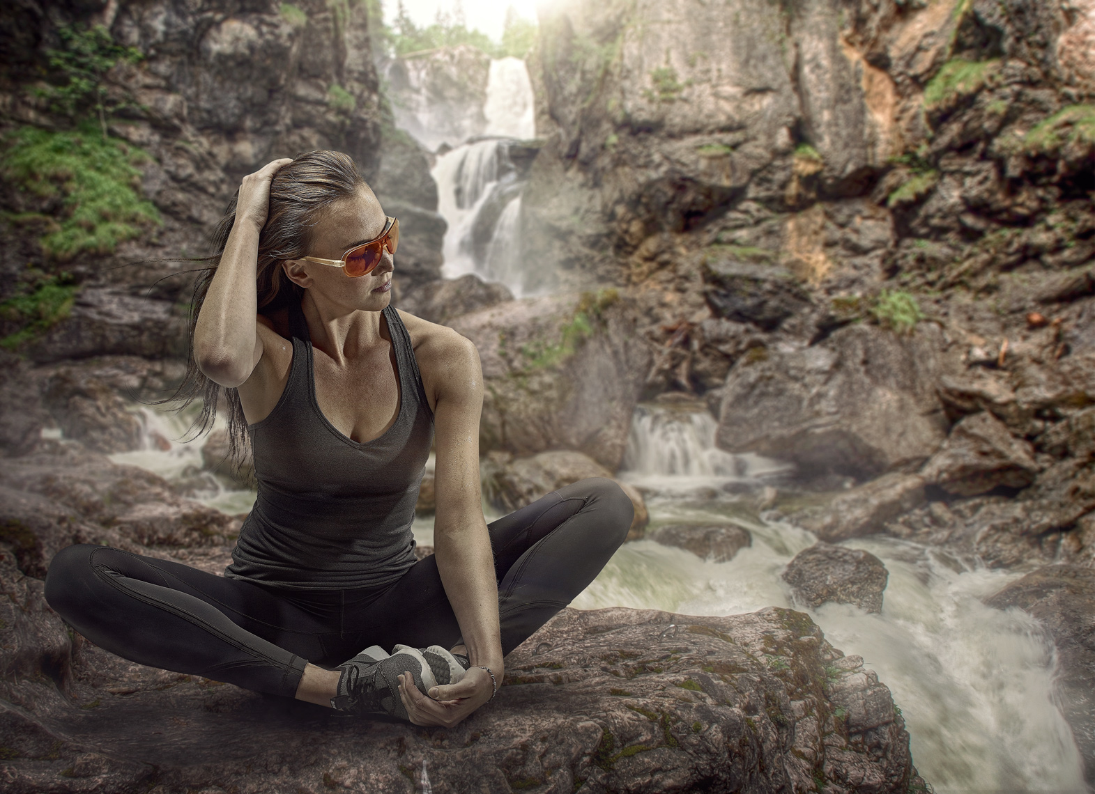 female hiker stretching on mountain trail with waterfall