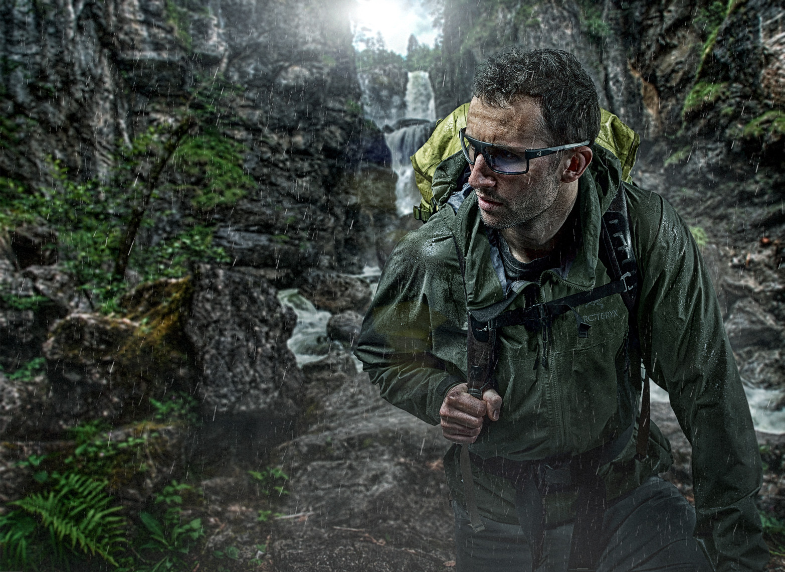 male hiker in the rain on a mountain waterfall